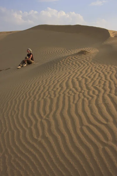 Человек, сидящий на песчаной дюне пустыни — стоковое фото
