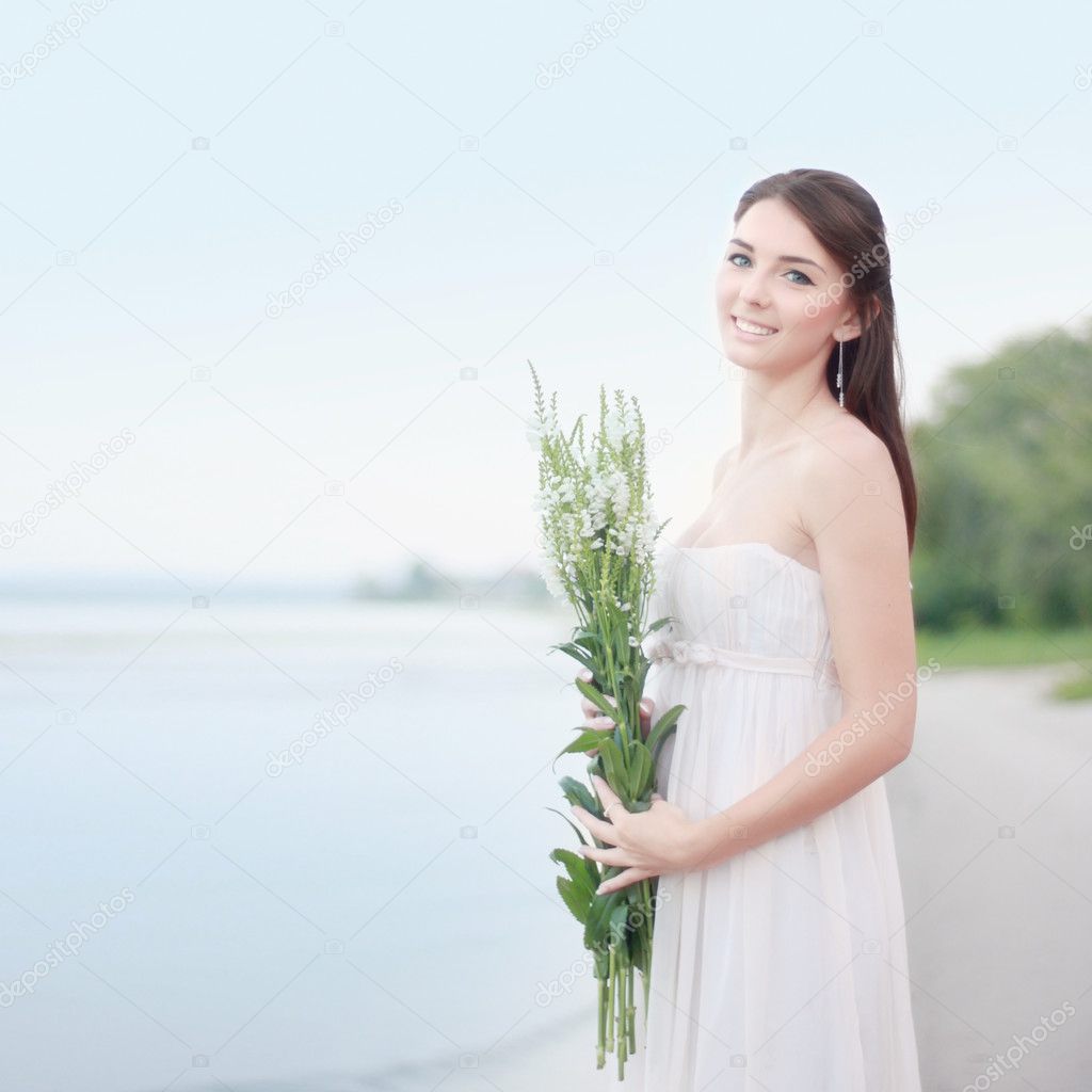 Young girl with white flowers on the beach