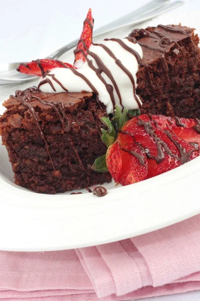 Chocolate brownies with cream and strawberries — Stock Photo, Image