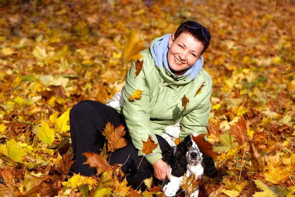 Женщина играет со своей собакой в осеннем парке — стоковое фото