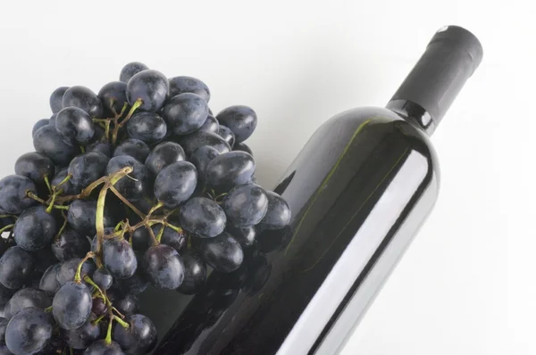 Bir şişe kırmızı şarap ve üzüm demet — Stok fotoğraf