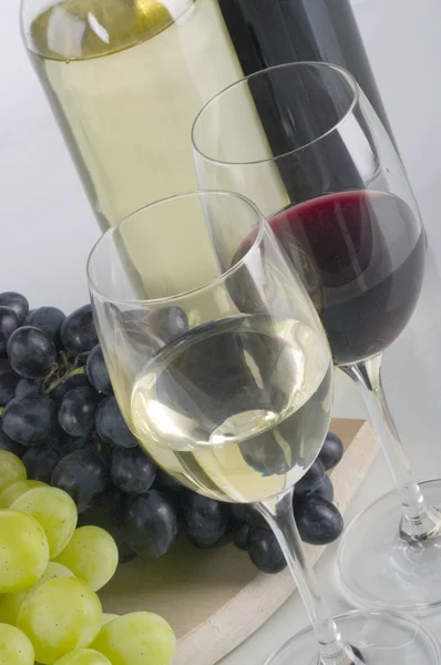 Glasses of white and red wine and grapes — Stock Photo, Image
