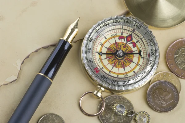 Złote pióro z kompasem i monety — Zdjęcie stockowe