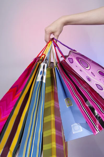Main féminine tenant des sacs à provisions colorés — Photo