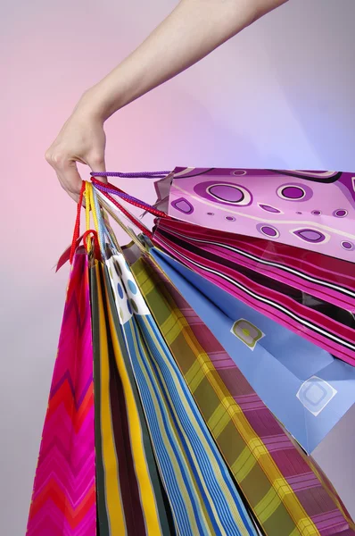 Main féminine tenant des sacs à provisions colorés — Photo