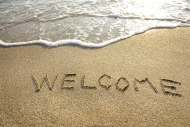 Welcome drawn in the sand with seafoam and wave clipart