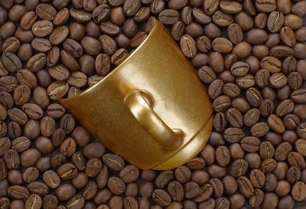 Gold cup with coffee beans — Stock Photo, Image