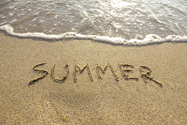 Summer drawn in the sand with seafoam and wave