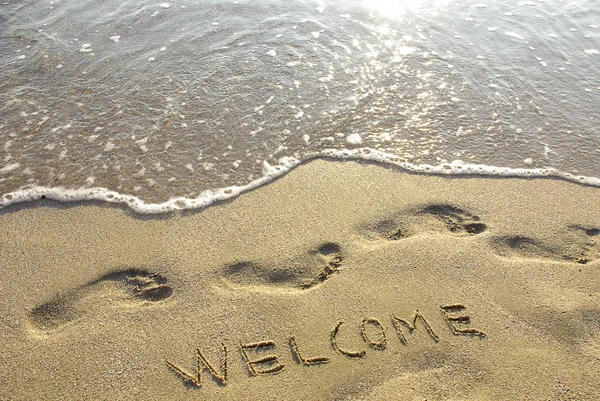 Bem-vindo desenhado na areia com seafoam e onda — Fotografia de Stock