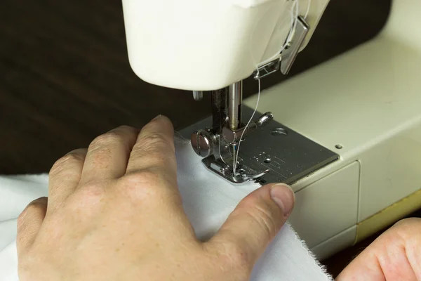 Mão guiando pano através de uma máquina de costura — Fotografia de Stock
