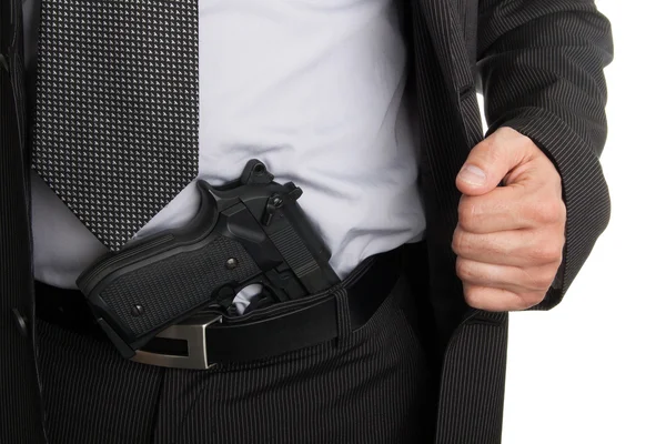 Мужчина в костюме показывает пистолет, спрятанный в штанах — стоковое фото