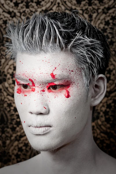 Young asian male with red paint fashion makeup