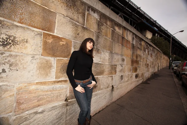 Jonge vrouw leunend tegen een muur zandsteen — Stockfoto
