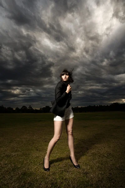 Stock image Young caucasian woman in a park with stormy background