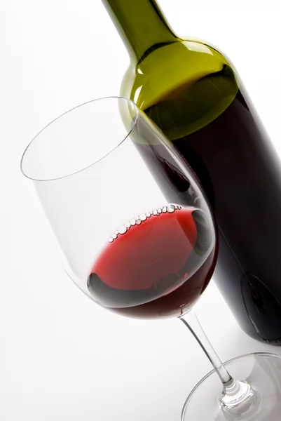 Glas rode wijn naast een fles — Stockfoto