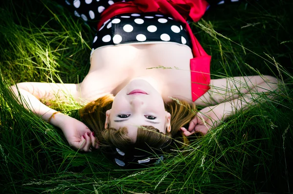 Menina encontra-se na grama verde fresca grossa — Fotografia de Stock