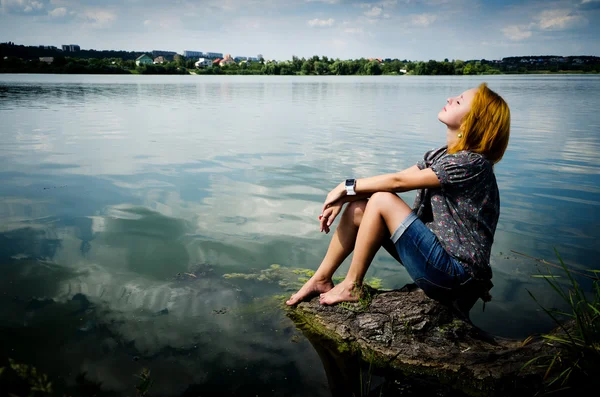 Meisje, zittend op het logboek in het meer. — Stockfoto