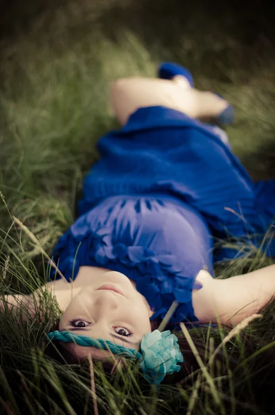 草で横になっている青いドレスの美しさ — ストック写真