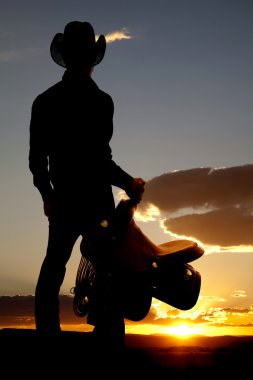 Cowboy holding saddle silhouette clipart