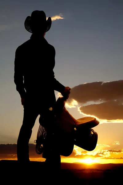 Cowboy holding saddle silhouette — Stock Photo, Image