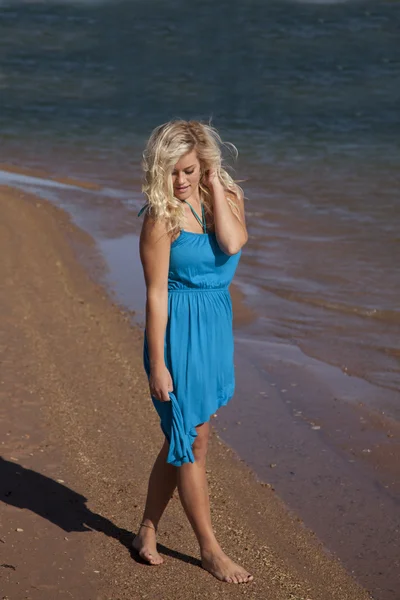 Mujer vestido azul caminar playa mirar hacia abajo —  Fotos de Stock