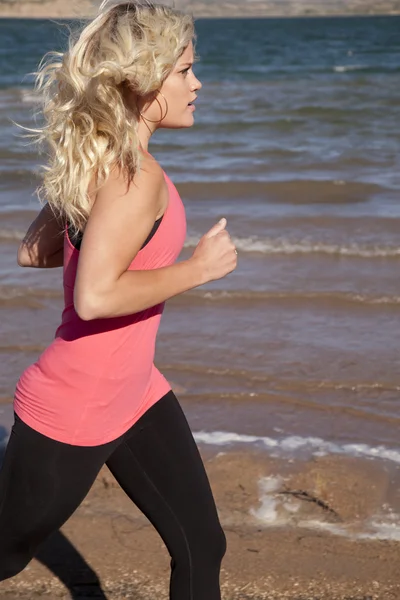 Woman running side by water — Stock Photo, Image