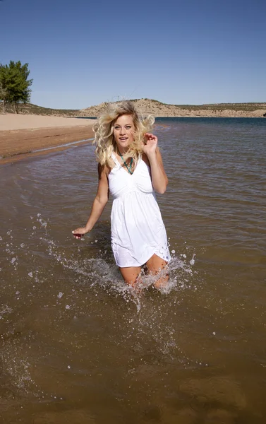 Vrouw witte jurk lopen in water — Stockfoto