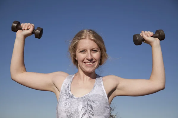 Woman weights up blue sky — Stock Photo, Image