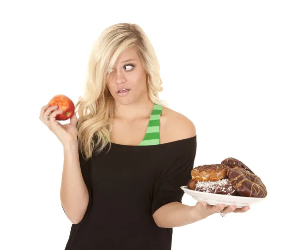 Kvinna med apple vill donut — Stockfoto