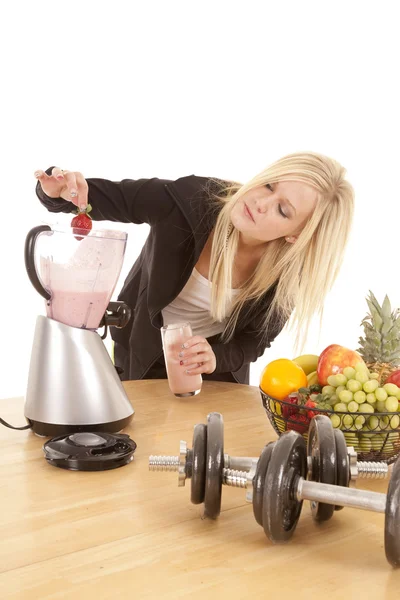 Woman putting strawberry in blender — Stock Photo, Image
