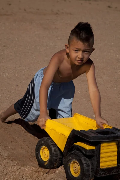 Мальчик и грузовик в песке — стоковое фото