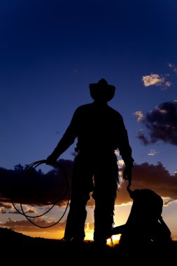 Cowboy with saddle on ground clipart