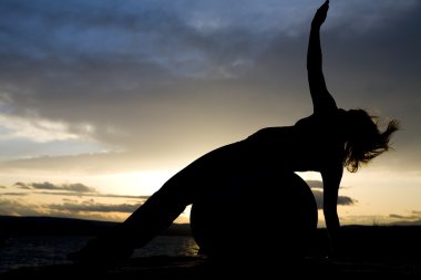 Silhouette of woman laying on ball clipart