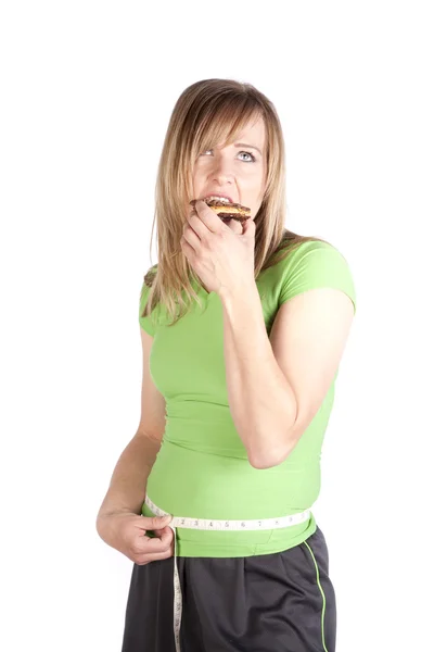 Woman eating snack and measuring waist — Stock Photo, Image