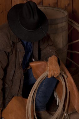 Cowboy kneeling by barrel head down close clipart