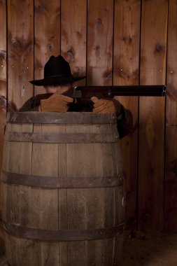 Cowboy shooting over a barrel clipart