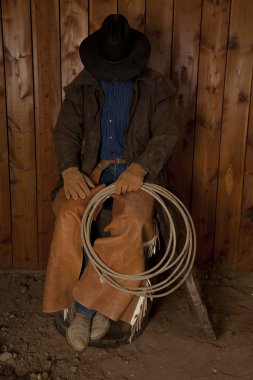 Cowboy sitting on barrel head down clipart