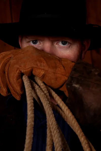 Cowboy tittar över handske med rep — Stockfoto