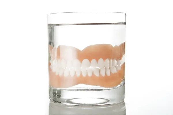 Glass with dentures — Stock Photo, Image