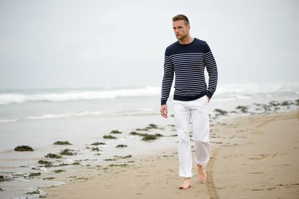 Jeune homme marchant sur la plage — Photo