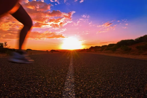 Mulher está executando enquanto o sol está a subir acima de uma estrada sem fim no australiano outback, monkey mia, Austrália Ocidental, Austrália — Fotografia de Stock