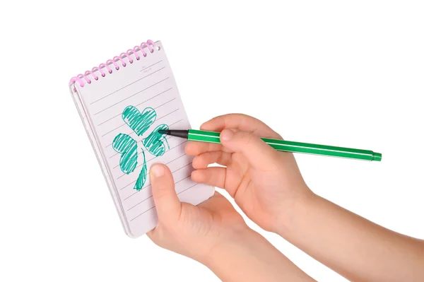 As mãos das crianças seguram caderno com um trevo pintado — Fotografia de Stock