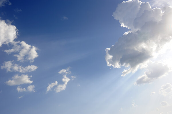 Sun beams over blue sky and clouds