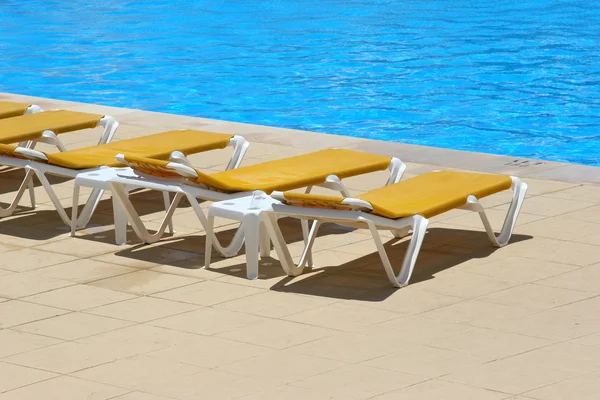 Pool restbeds runt en pool med blått vatten bakgrund — Stockfoto