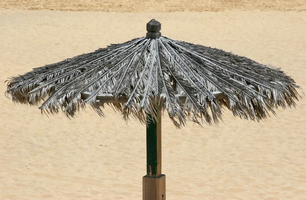 Sluneční clonou na pláži s pískem na pozadí — Stock fotografie