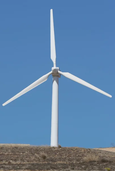 Molen macht windgenerator met land tegen blauwe hemel — Stockfoto