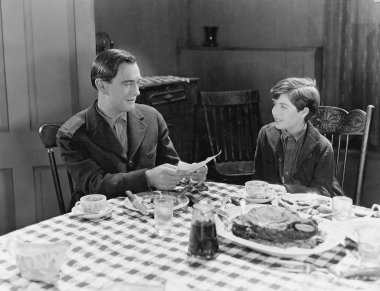 Portrait of father and son at dinner table clipart