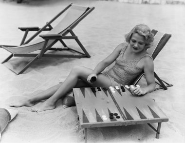 Woman playing backgammon on beach clipart
