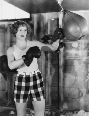 Female boxer using punching bag clipart