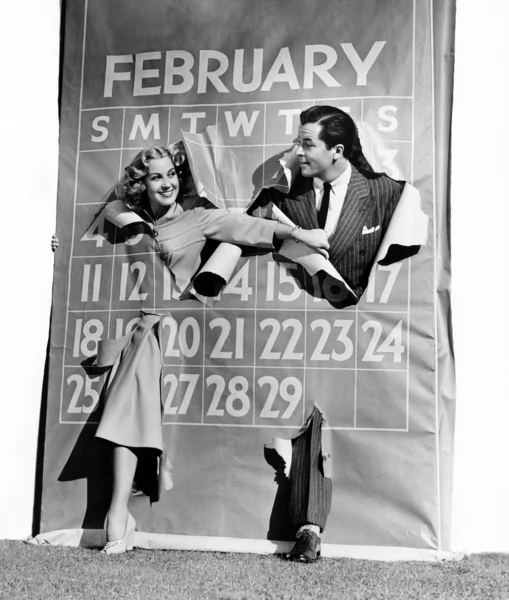 Couple bursting through leap year calendar — Stock Photo, Image